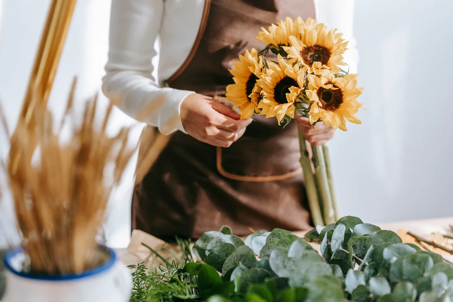A florist arranging sunflowers at a worktable.